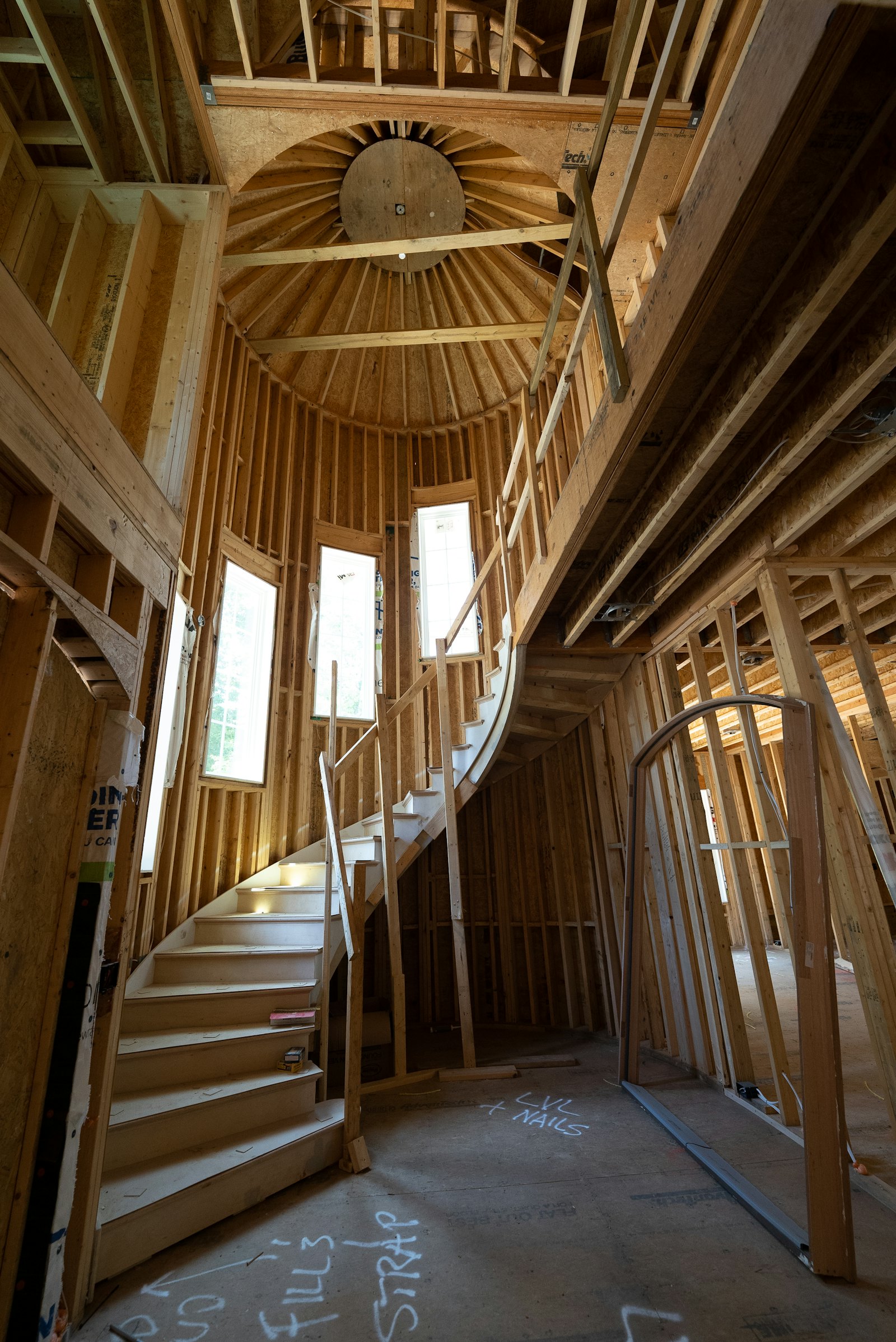 A curved staircase inside a timber-framed house under construction