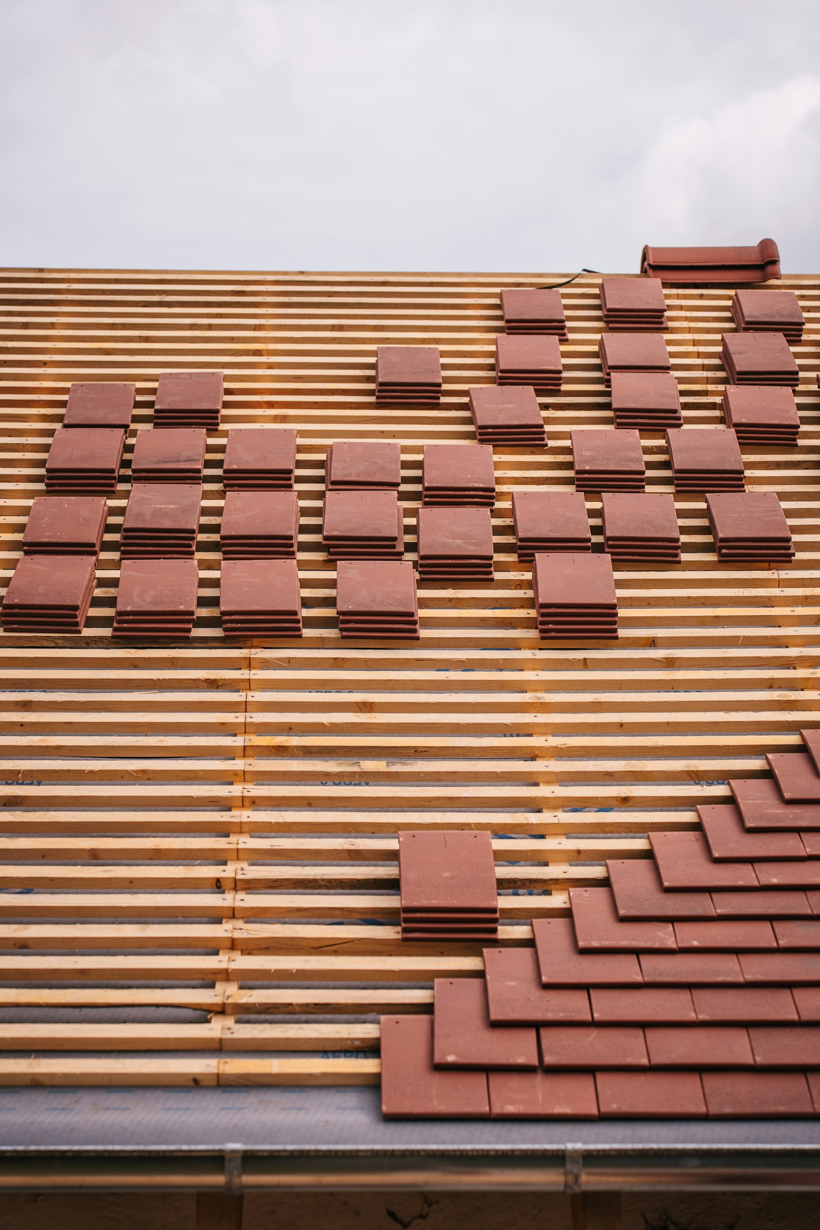 Clay roof tiles stacked on timber battens during a roof build